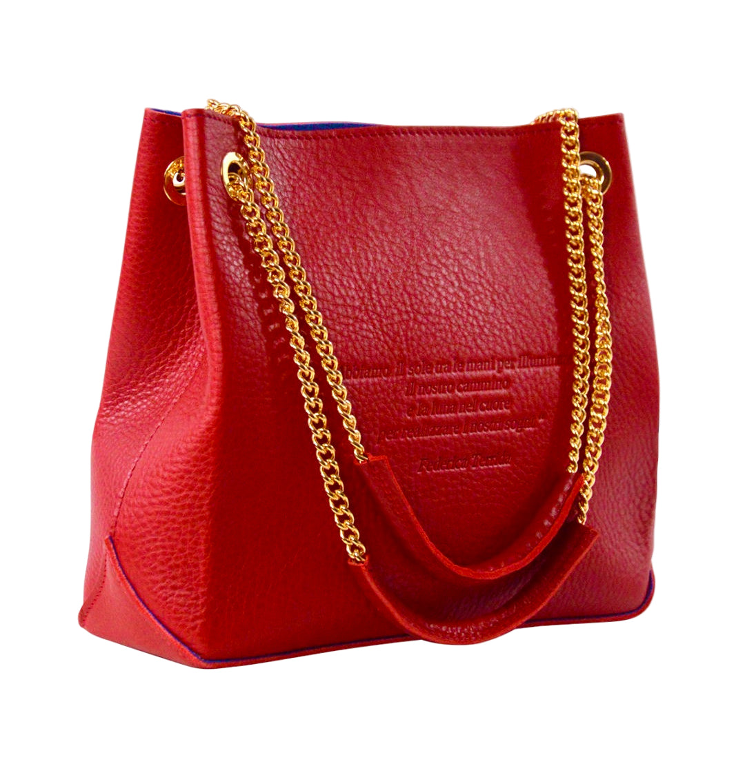 A red woman's handbag with gold chain handles, made from vegetable tanned leather, displayed against a white background.